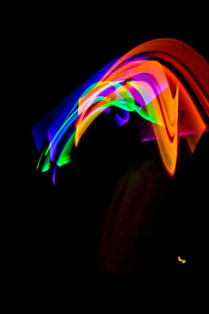 Streaks of vivid blue, green, oranges and red arc across a black background